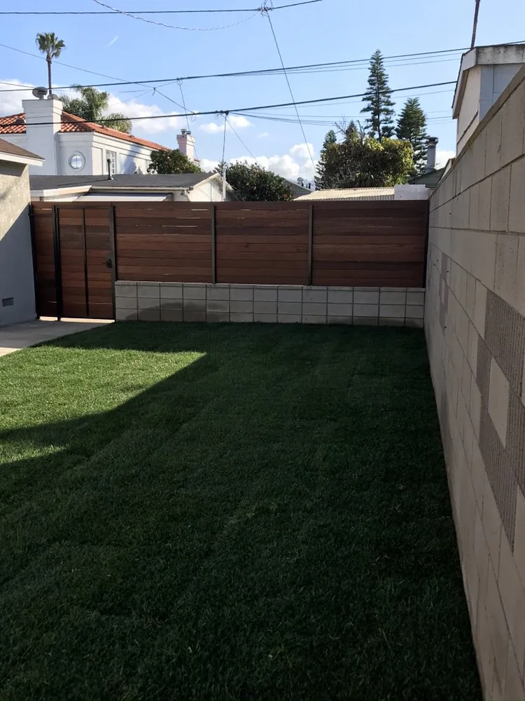 Block wall, wood fence, and new turf built by Islander Concrete